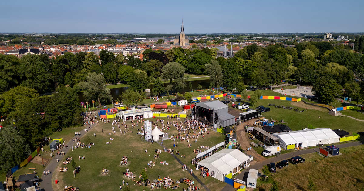 Luchtfoto van het Full Color Festival in het Stadspark van Kampen, met het hoofdpodium, tenten en bezoekers op het grasveld